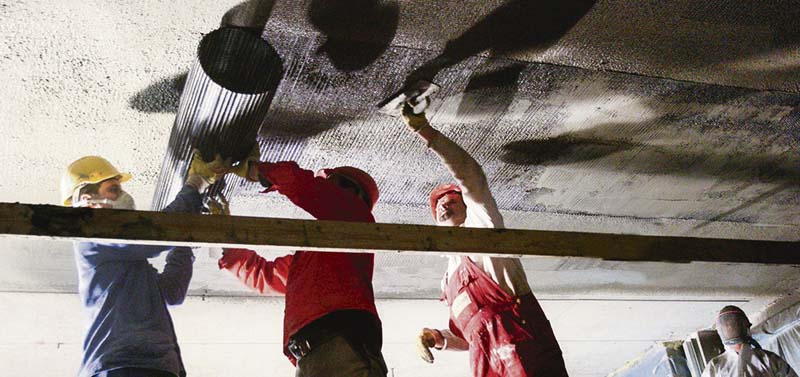 Sanierung einer Betondecke mit Textilbeton. Im Bild wird eine Textilbahn in das frische Betonbett eingebracht. (Foto: Schladitz)