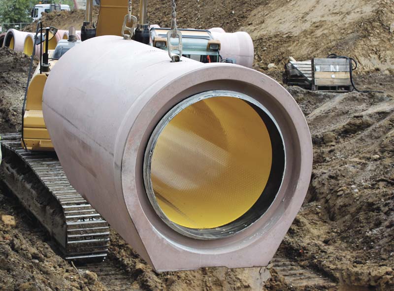 Sicheres Einheben eines Perfect Pipe DN1000 Fußrohres mit Glockenmuffe unter Zuhilfenahme eines am Bagger befestigten Kettengehänges.  (Foto: Bernhard Müller Betonsteinwerk GmbH)
