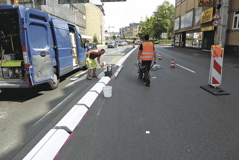 Auf elf Zentimeter Höhe abgeschnittene Flachbordsteine lassen sich nachträglich schnell und einfach auf die Asphaltfläche aufbringen.   (Foto: Meudt Betonsteinwerk GmbH)